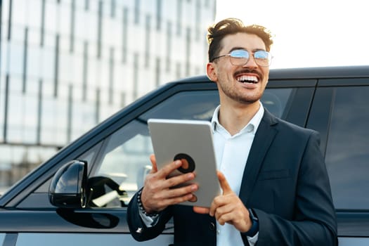 Young businessman using digital tablet while standing outdoors close up