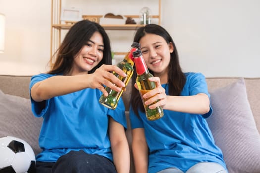 A lesbian couple cheers football and celebrate together for their favorite Euro football team. A young female couple cheers football on TV together in the living room on match day..