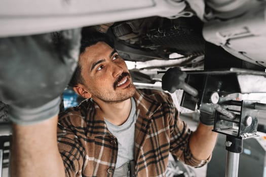 Auto mechanic repairs running gear of a car in car service close up