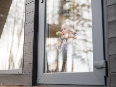 Baby boy standing by the patio window