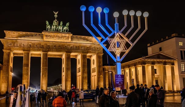 Belin, Germany - 21 December 2022: Brandenburg Gate and lightning Jewish menorah on a square against Gates in Berlin at night