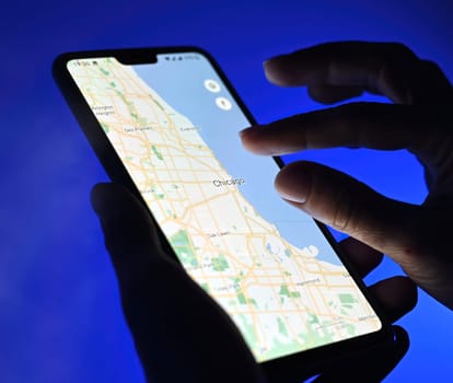 Poznan, Poland - 13 January: Girl using google maps app on a smartphone against blue background, close up view. Traffic Chicago city.