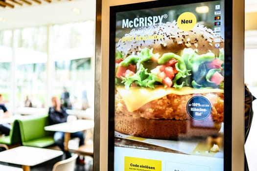 Berlin, Germany - 10 April 2023: self-order counter with advertising inside of restaurant McDonald's