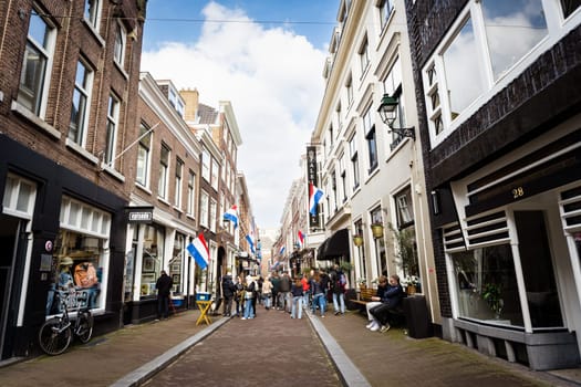 Hague, Netherland - 09 April 2023: Central Street with shops of Hague in Holland. Street with national flags on a building's.