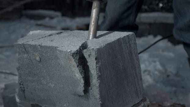 Man drills cement blocks. Clip. Worker splits cement blocks at construction site with hammer drill. Breaking apart cement blocks with drill.