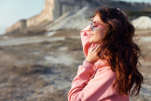 Woman in pink shirt and sunglasses admiring majestic mountain landscape under clear blue sky