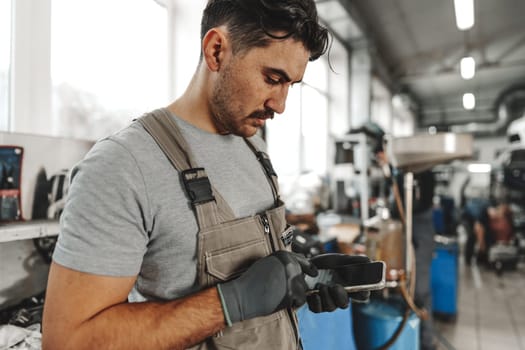 Close up photo of automechanic using cellphone at workplace in car service