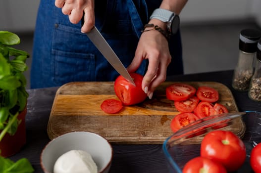 Female Hands Cut Tomatoes On A Board Next To Mozzarella