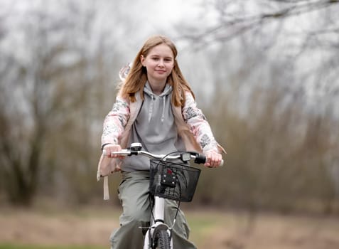 Smiling Girl Rides Bicycle In Spring With Blurred Park Background