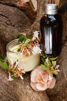 Fragrance oil in caramel bottle ,spa scented candle and flowers. Rustic background, Vertical photo