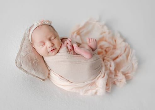 Newborn Girl Wrapped Up, Smiles In Her Sleep In Beige Tones Photo