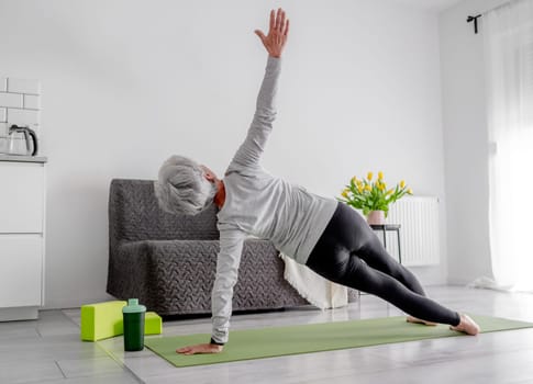 Calm Home Exercises In A Bright Room, A 70-Year-Old Woman Practices Yoga