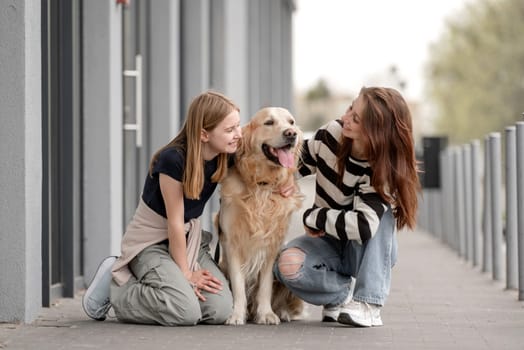 Two Girls Play With A Golden Retriever, Sitting Outside In The Fall