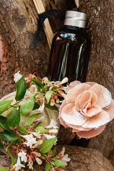 Fragrance oil in caramel bottle decorated with mixed natural and fabric flowers. Spa concept