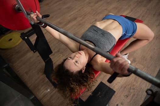 Middle aged woman doing bench press at the gym