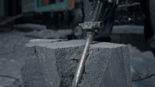 Man drills cement blocks. Clip. Worker splits cement blocks at construction site with hammer drill. Breaking apart cement blocks with drill.