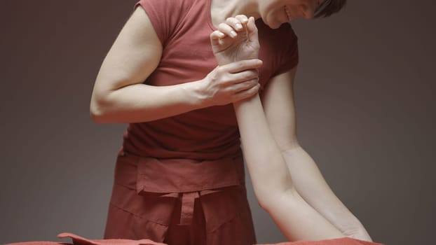 Close-up of woman massaging client's hand. Action. Masseur kneads the client's hand in spa salon. Relaxing hand massage at spa.