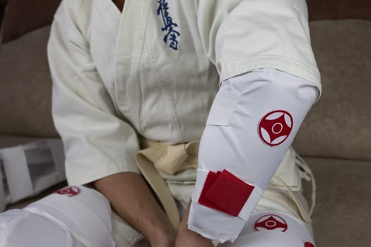 Kyokushinkai karate athlete wears elbow protection, protective equipment for martial arts sparring, health protection in karate