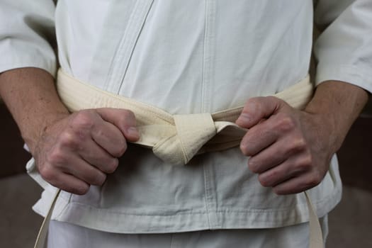 White belt of an athlete in Kyokushin karate, an athlete ties the belt on kimono before the competition