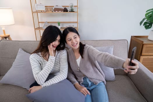 Asian lesbian couple taking selfie at home. Concept of technology and companionship.