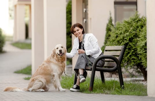 Girl Relaxes On Bench With Her Golden Retriever In Warm Weather