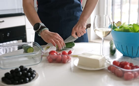 Woman'S Hands Are Slicing Cucumber For Greek Salad With A Glass Of White Wine Nearby