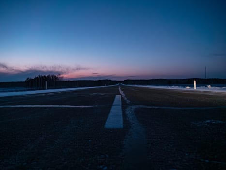 Empty rural road at twilight in winter with clearing skies