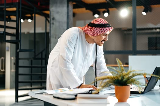 Young muslim businessman in traditional outfit working at the table in office clsoe up