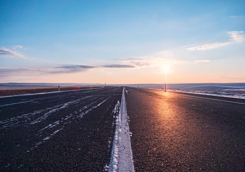 Empty rural road at sunsetin winter with clearing skies