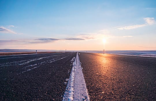 Empty rural road at sunsetin winter with clearing skies