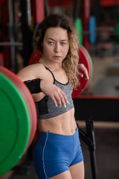 Middle aged woman posing at the barbell in the gym