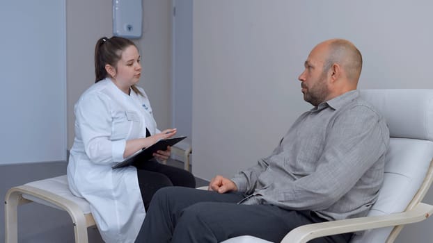 Doctor working in the office and giving recommendations to the patient. Clip. Young female doctor explaining symptoms to male patient, health care and assistance concept