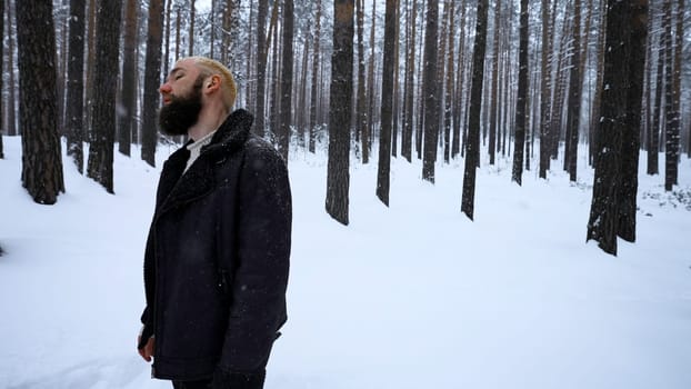 Young man in winter woods looking lost and frustrated. Media. Man in cold clothes in severe winter temperatures trying to survive