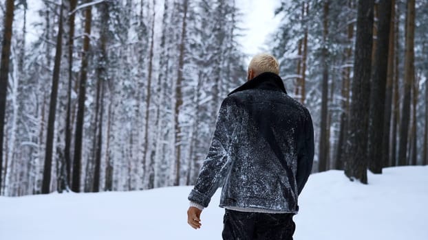 Lone man walking through snow. Media. Young guy with snow on his jacket feeling alone and isolated in cold forest