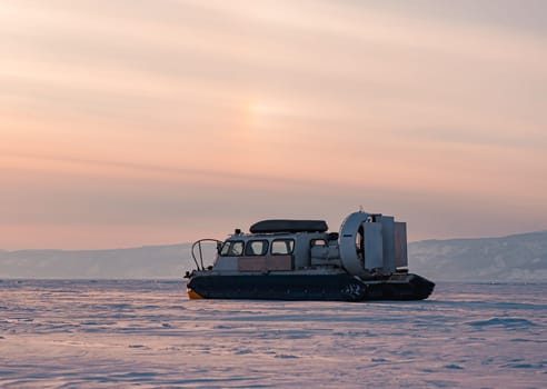 Hovercraft standing on snow covered ice surface of Lake Baikal at dusk.