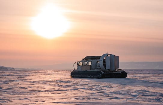 Hovercraft standing on snow covered ice surface of Lake Baikal at dusk.