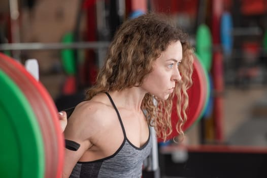 Middle-aged woman doing squats with a barbell in the gym