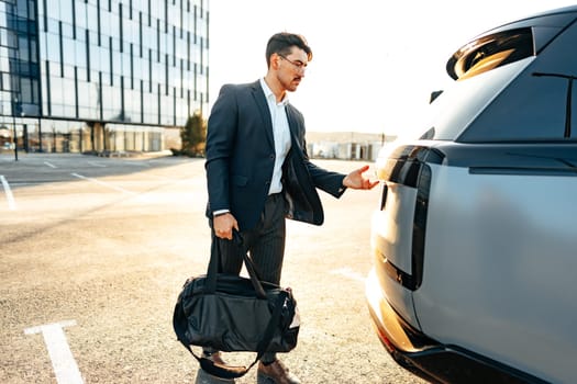 Successful businessman taking luggage from the car trunk outdoors