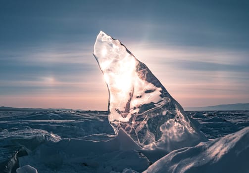 The serene landscape of Lake Baikal in winter, featuring captivating, transparent ice formations under a bright sky with the sun shining brightly above.