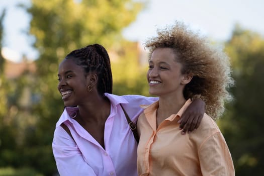 Side view portrait of multiethnic friends girls enjoying time together in a park.