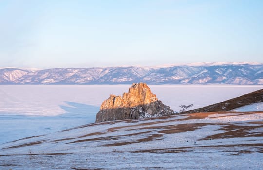 Shamanka rock on Olkhon island at sunset. Winter landscape. Popular touristic destination. Natural landmark.