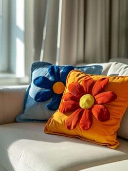 A yellow pillow sits on a white couch. The pillow is placed on the couch in front of a window, and a vase with a red flower is on the table next to the couch. Concept of warmth and comfort