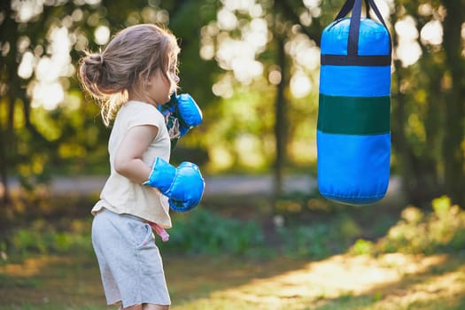 Charming child doing boxing in the backyard on the Sunset.