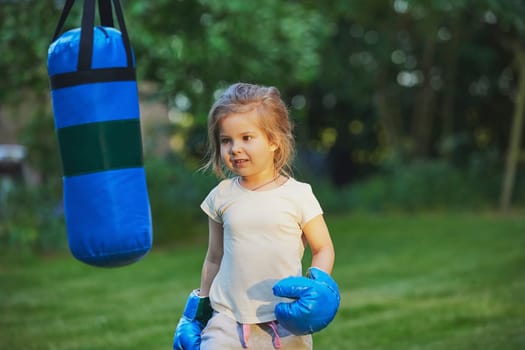 Charming child doing boxing in the backyard on the Sunset.