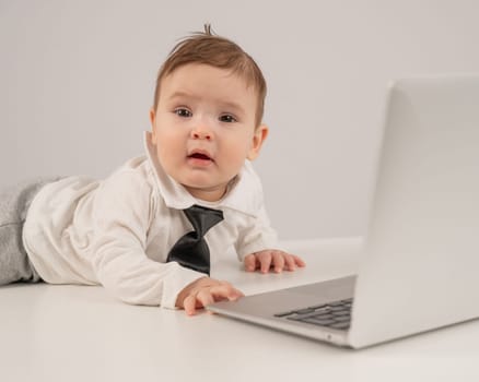 Cute baby boy in a tie working at a laptop