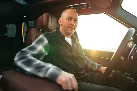 Smiling man in casual clothes sitting in luxury car, portrait