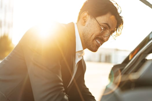 Successful businessman taking luggage from the car trunk outdoors