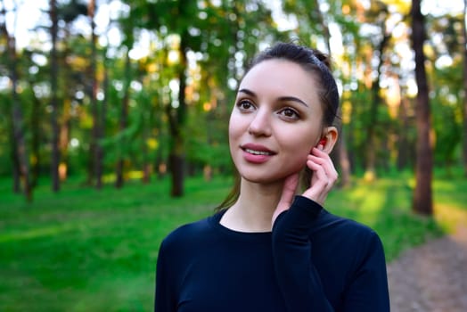 Portrait of a young woman smiling happily listening to music Among the trees in a serene forest , enjoying a peaceful moment in the lap of nature.