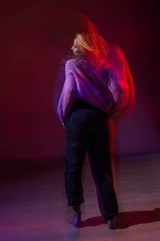 A young woman dances contemporary dances in blue and red light. Long exposure. Vertical photo