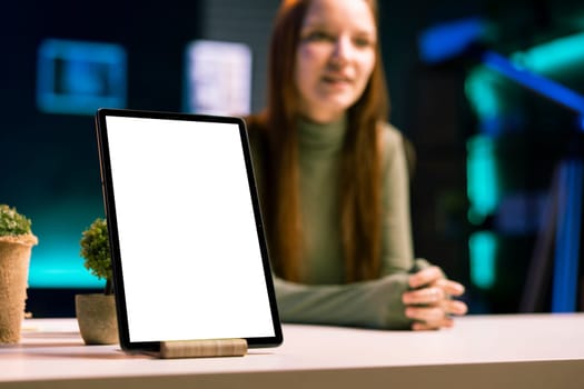 Focus on mockup tablet with gen Z teenager in blurry background doing review, comparing features. Close up shot of isolated screen portable device analyzed by influencer, filming online video